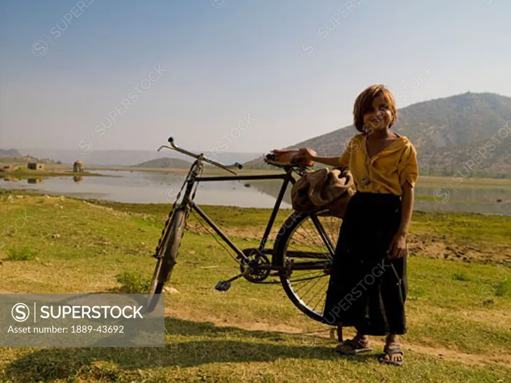 Rajasthan,India;Girl standing by a bicycle