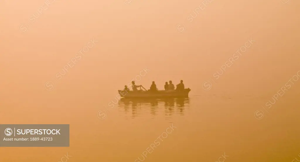 The Ganges,Varanasi,India;Man rowing family in a canoe on the river