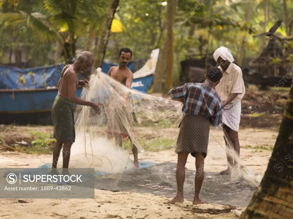 Kerala,India;Fishermen untangling fishing nets on the beach
