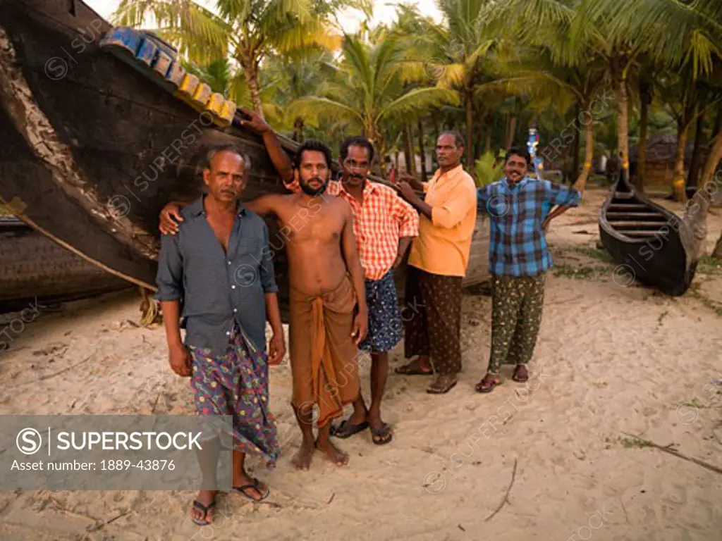 Kerala,India;Fishermen standing next to boat looking at the camera