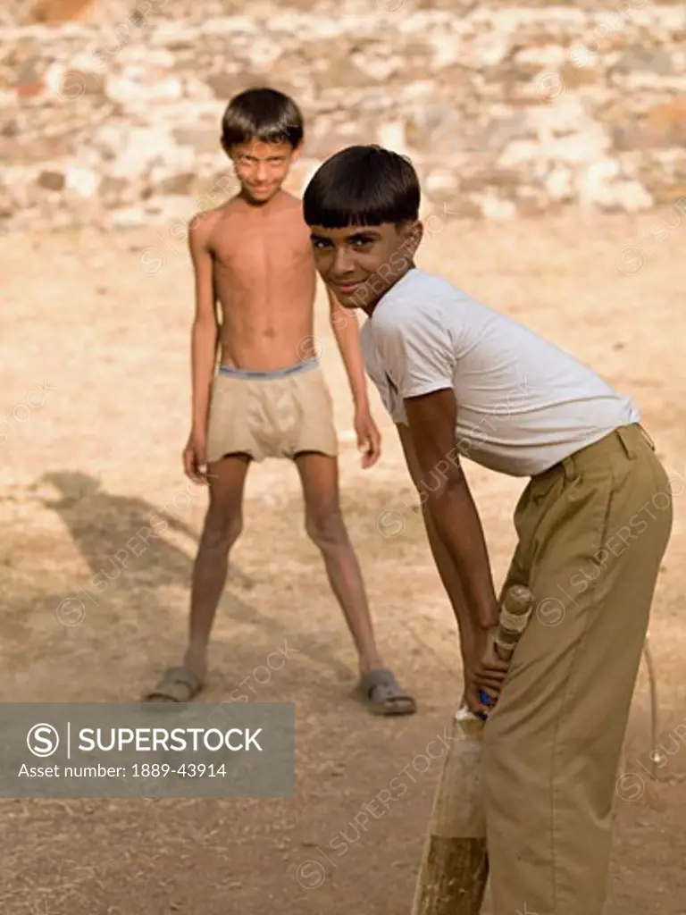 Aravalli Hills,Rajasthan,India;Two boys playing cricket,using makeshift equipment 
