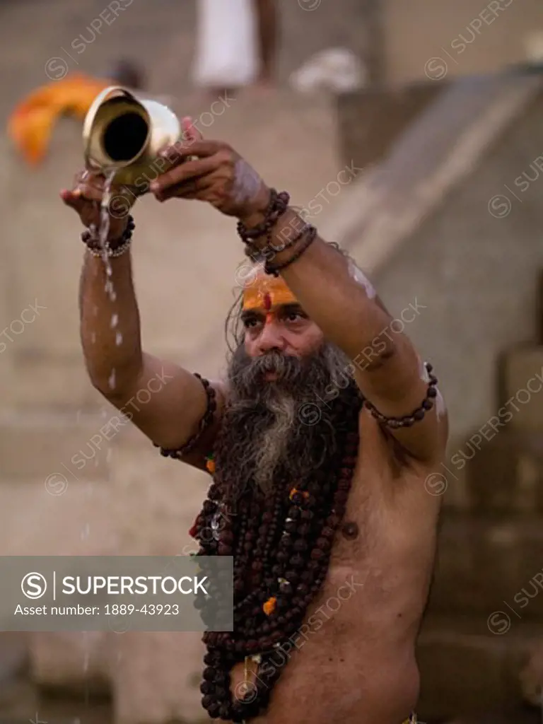 The Ganges River,Varanasi,India;A Sadhu pouring libations into the Ganges