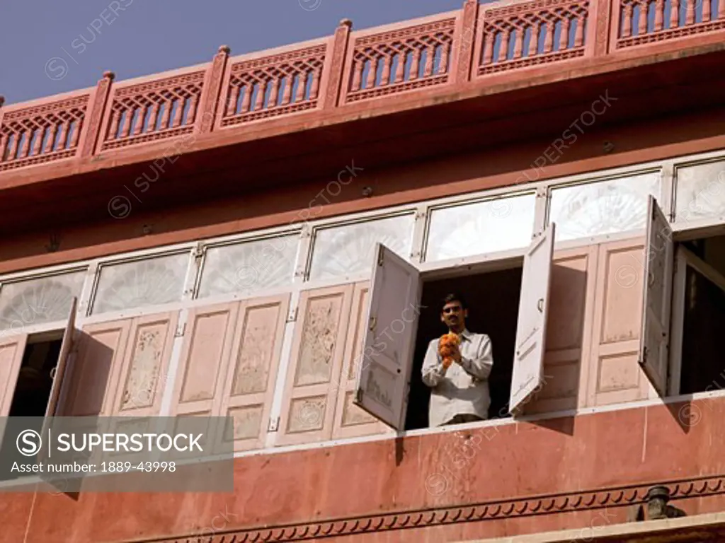 Jaipur,Rajasthan,India;Man standing at window,holding flower garland