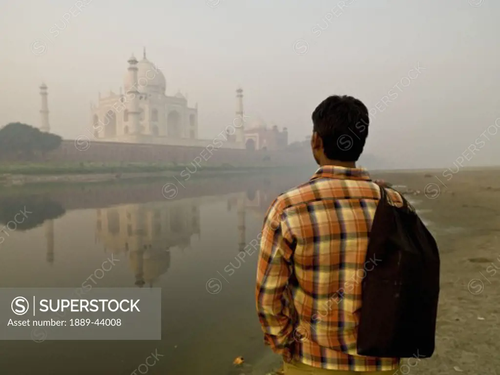 Taj Mahal,Agra,India;Young man standing at water's edge,looking at the Taj Mahal