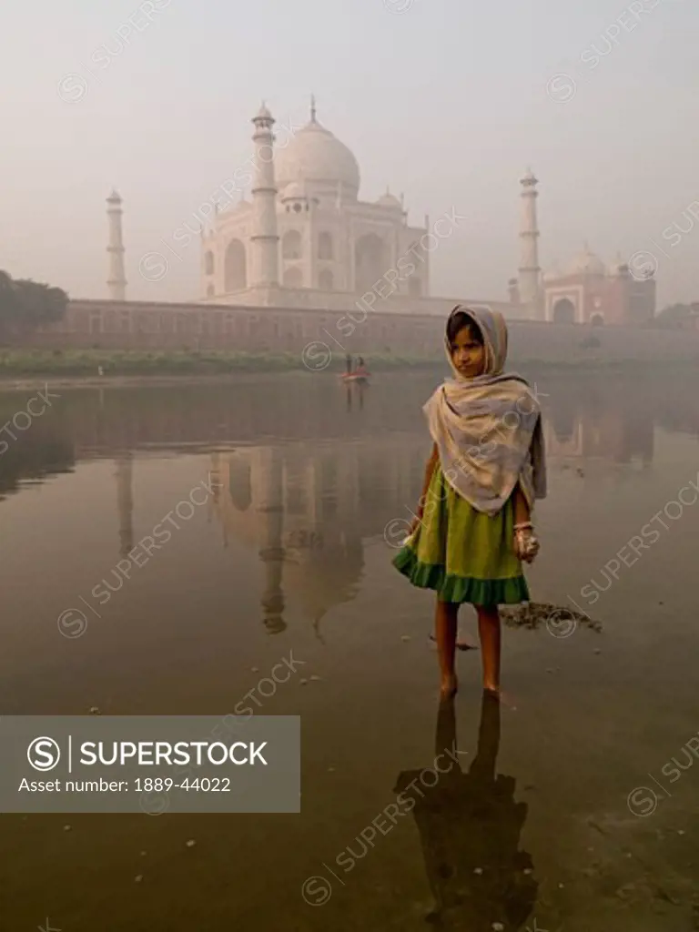 Taj Mahal,Agra,India;Portrait of young girl standing in the river,with the Taj Mahal behind her