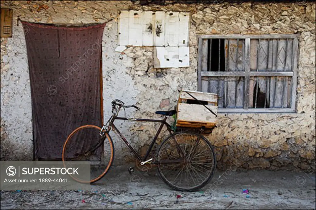 Pwani Mchangani,Zanzibar,Africa;Old bicycle outside dilapidated stone building