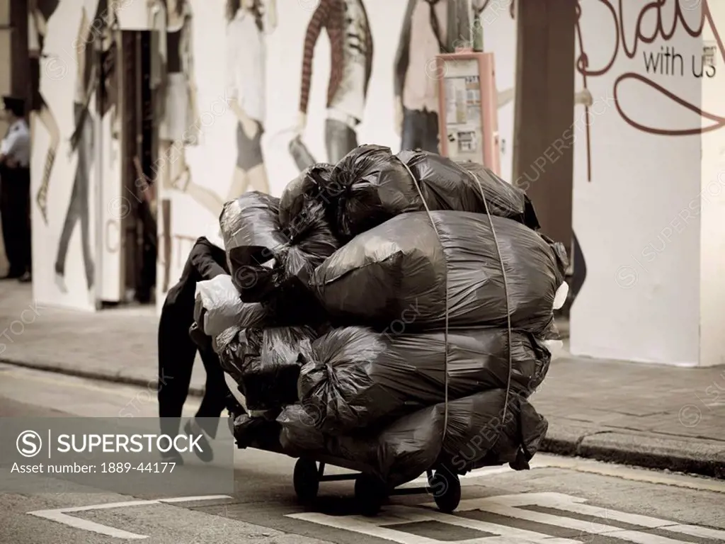 Person carting garbage bags down a street
