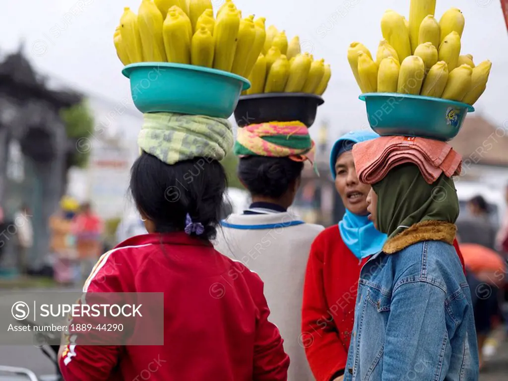 Women carrying bowls of corn on heads