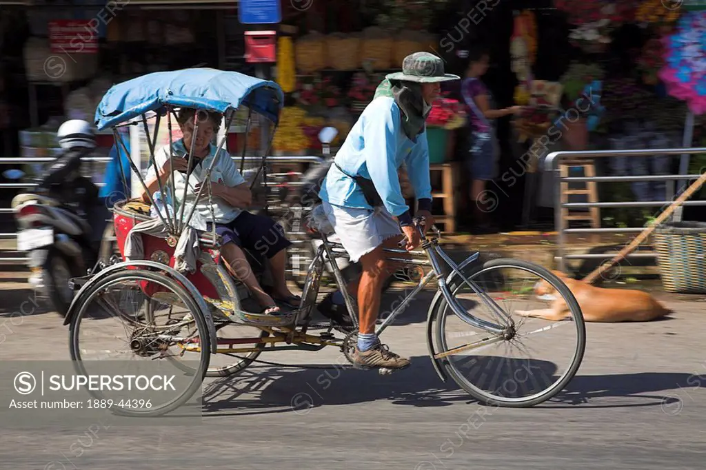 Man on a tricycle transporting a woman