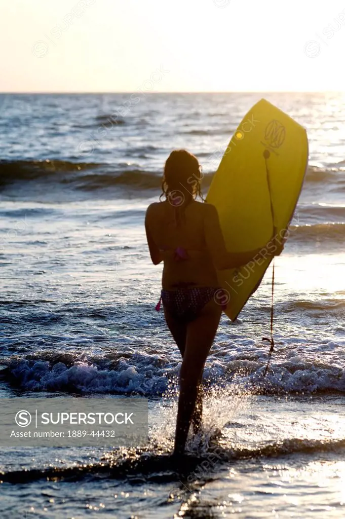 Woman on beach carrying bodyboard