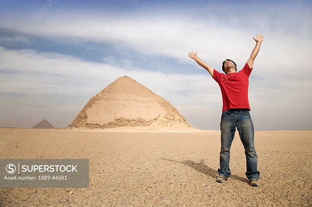 Man standing near the Pyramids with his arms up