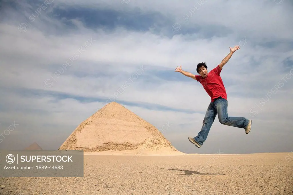 Man jumping in air with Pyramids in background