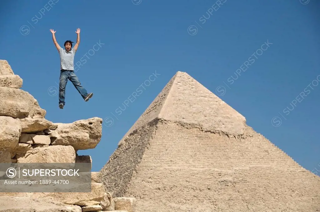 Man jumping on part of a Pyramid in the desert