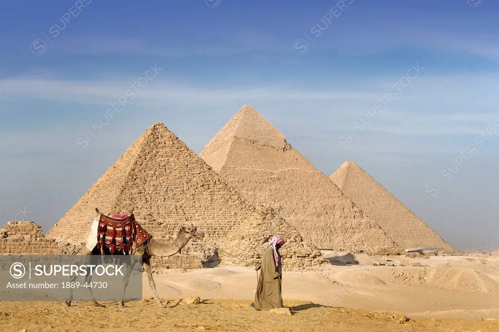 A man and camel walking near the Pyramids