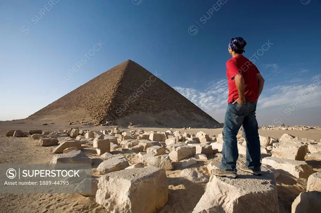 A man standing near a Pyramid in the desert