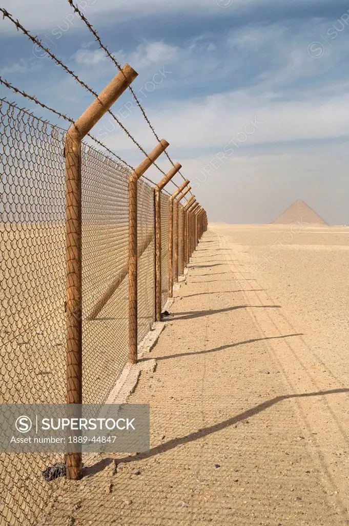 A barbed wire fence with Pyramid of Giza in background