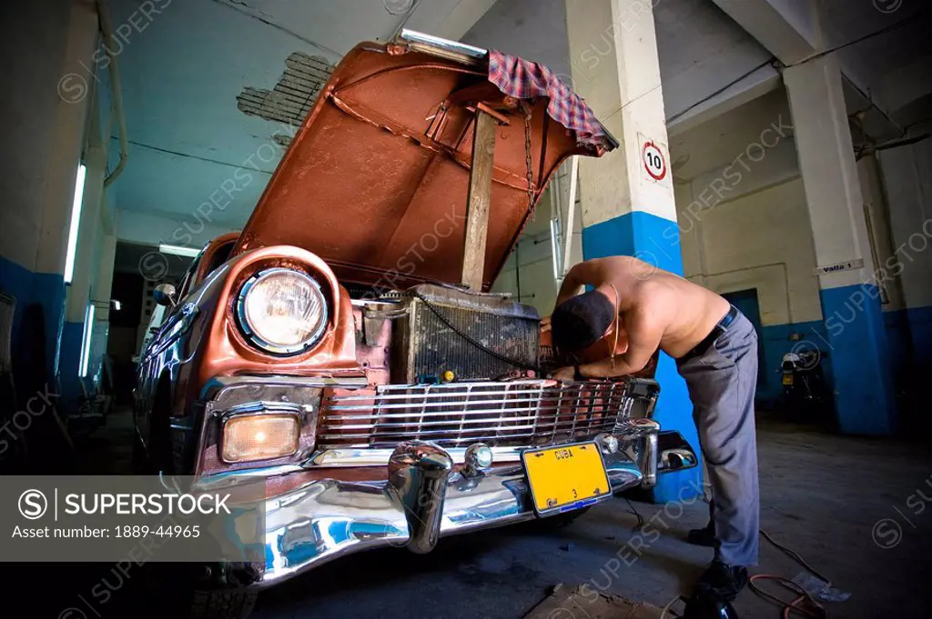 Mechanic fixing a car in Havana garage