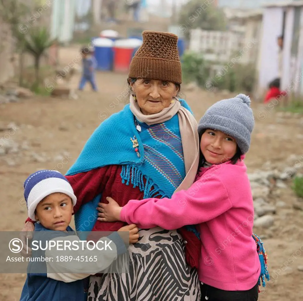 Children hugging senior woman, Lima, Peru
