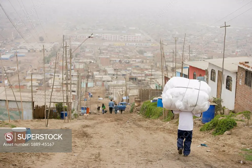 Person carrying load down rural road, Lima, Peru