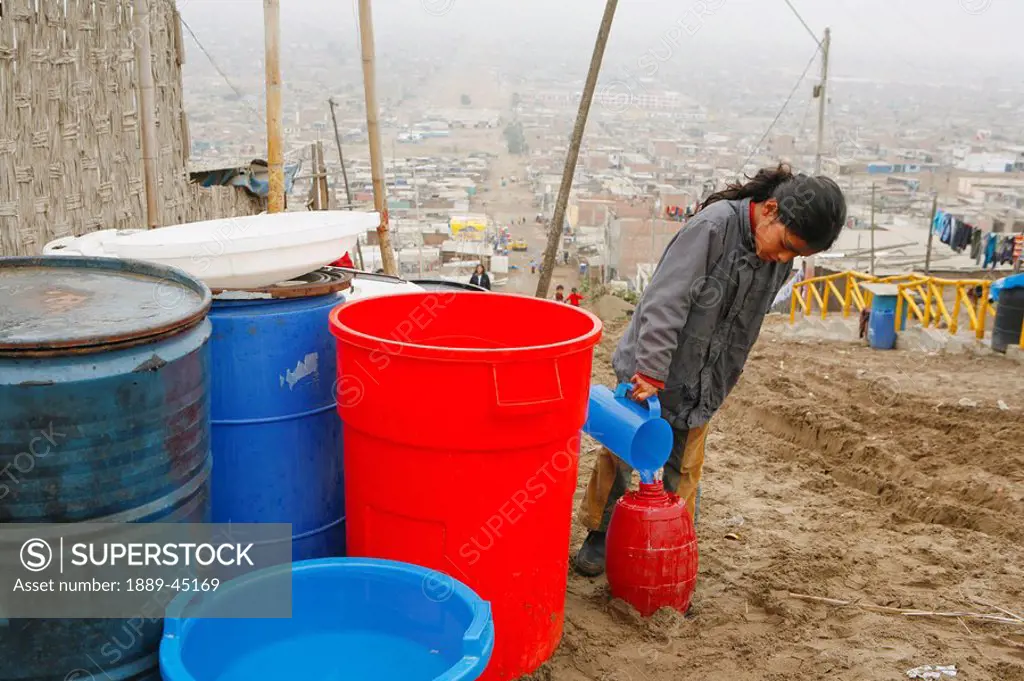 Young girl pouring water into bucket, Lima, Peru
