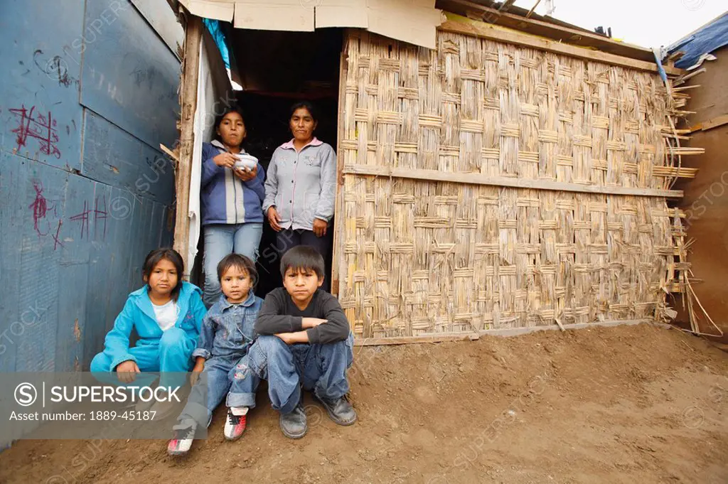 Family members at entrance to slum dwelling, Lima, Peru