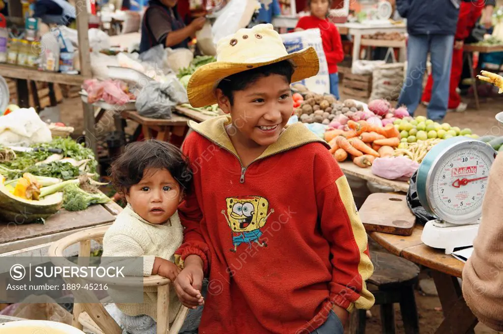 Young boy with baby in marketplace, Lima, Peru