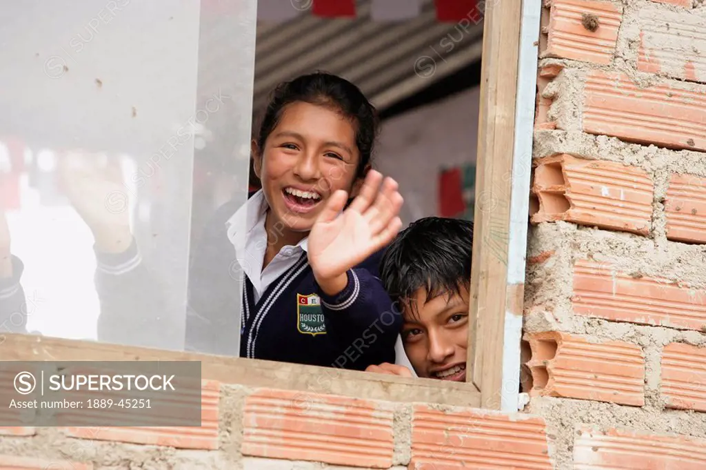 Children waving from window, Lima, Peru