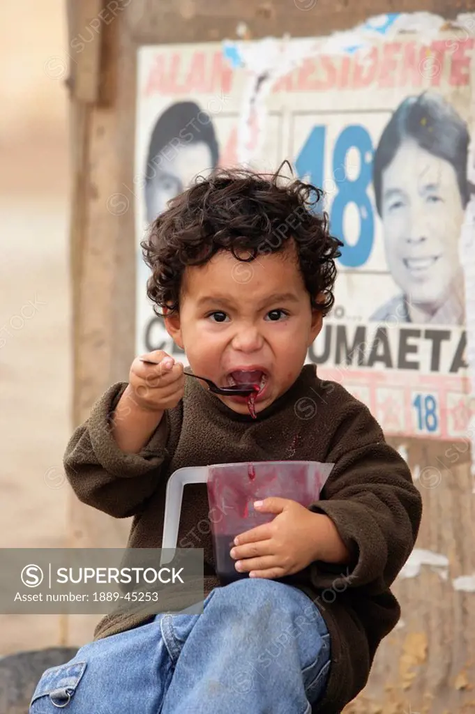 Young boy eating, Lima, Peru