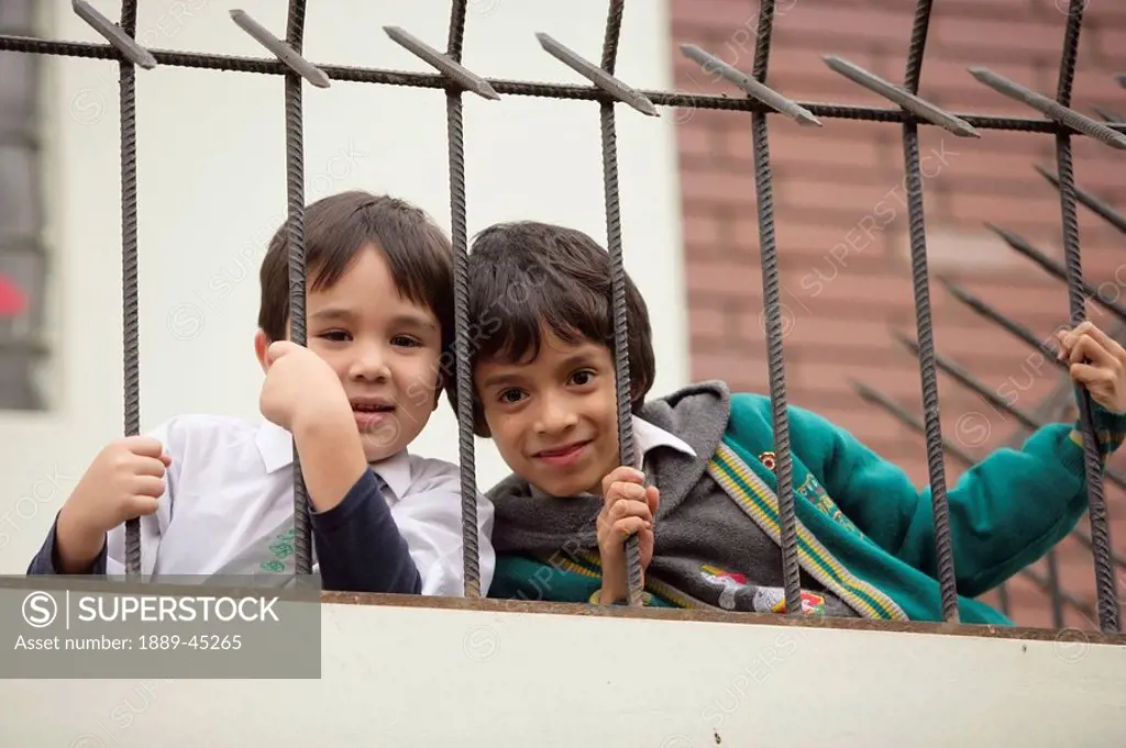 Young boys looking through fence, Lima, Peru