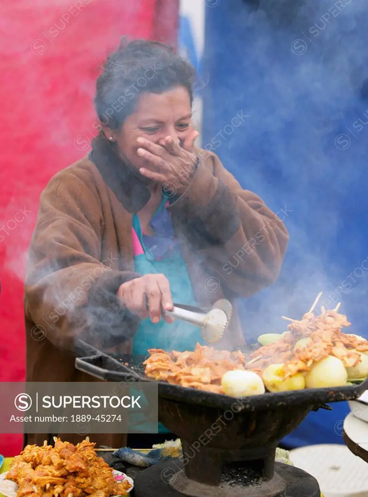 Woman cooking outdoors, Lima, Peru
