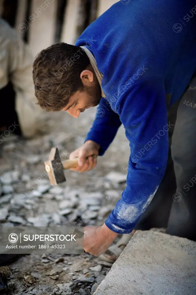 Man hammering rock with a hammer and chisel