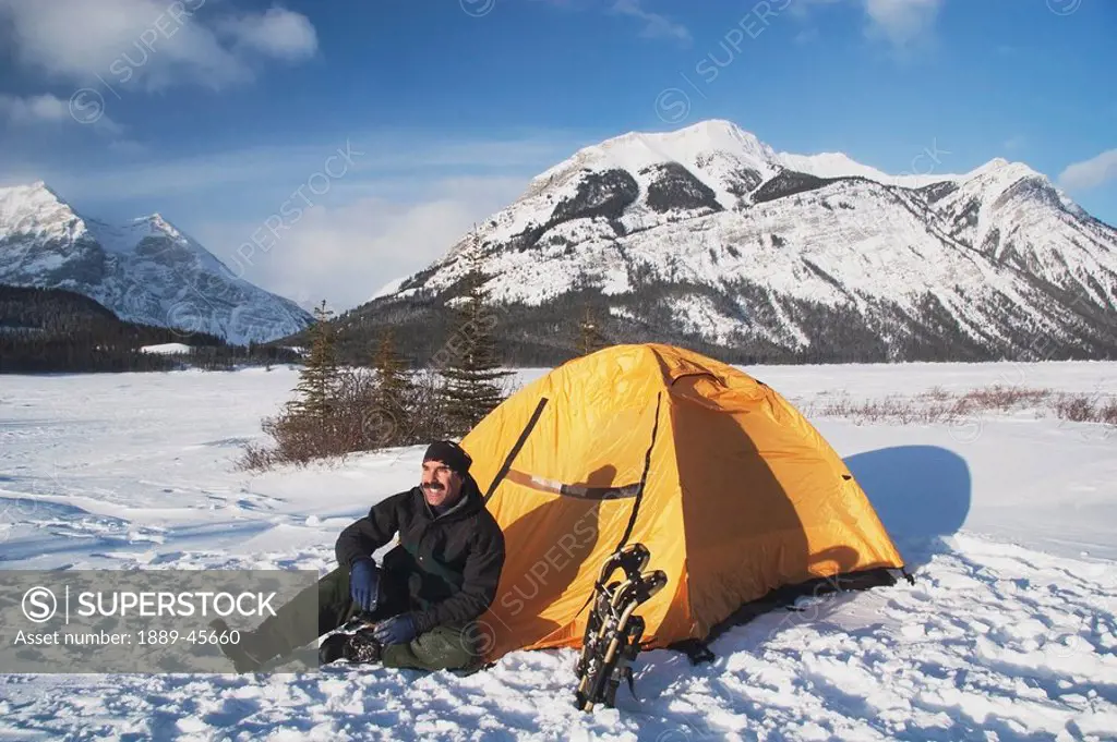 Man sitting by his tent in the snow in the winter