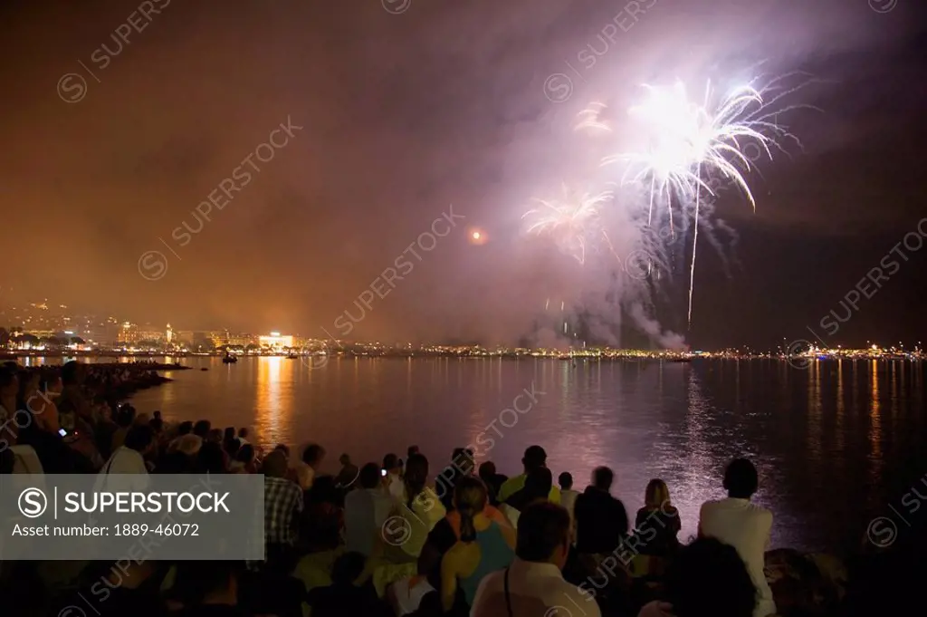cannes, provence, france, a crowd watches fireworks over the water from the shore
