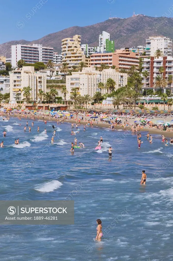 benalmadena, malaga province, costa del sol, spain, people in the ocean and on the beach and hotels along the coast at playa de torre bermeja