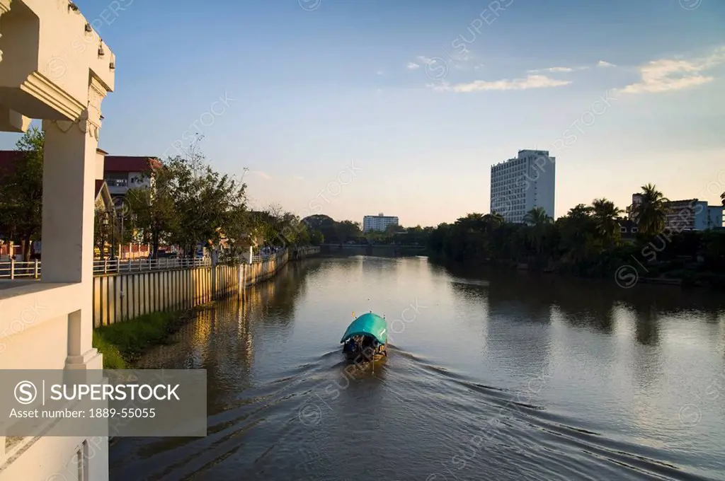 Chiang Mai, Thailand, A Boat Traveling Down The River In The Evening