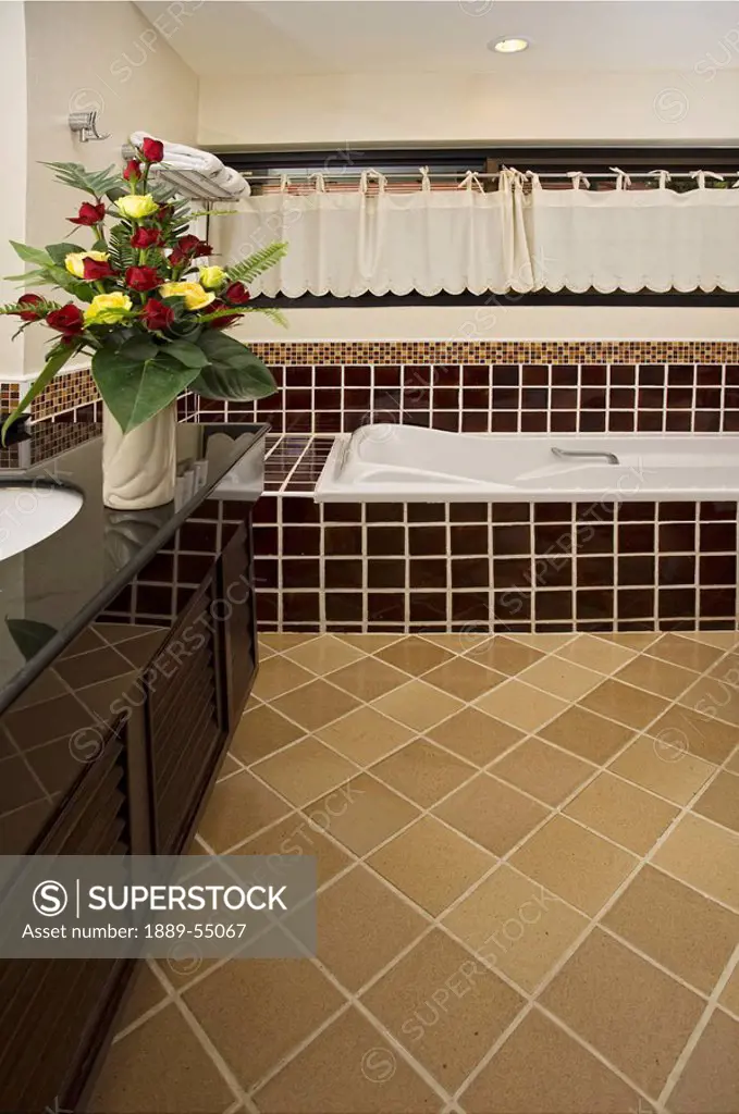 A Hotel Bathroom With A Flower Arrangement On The Counter