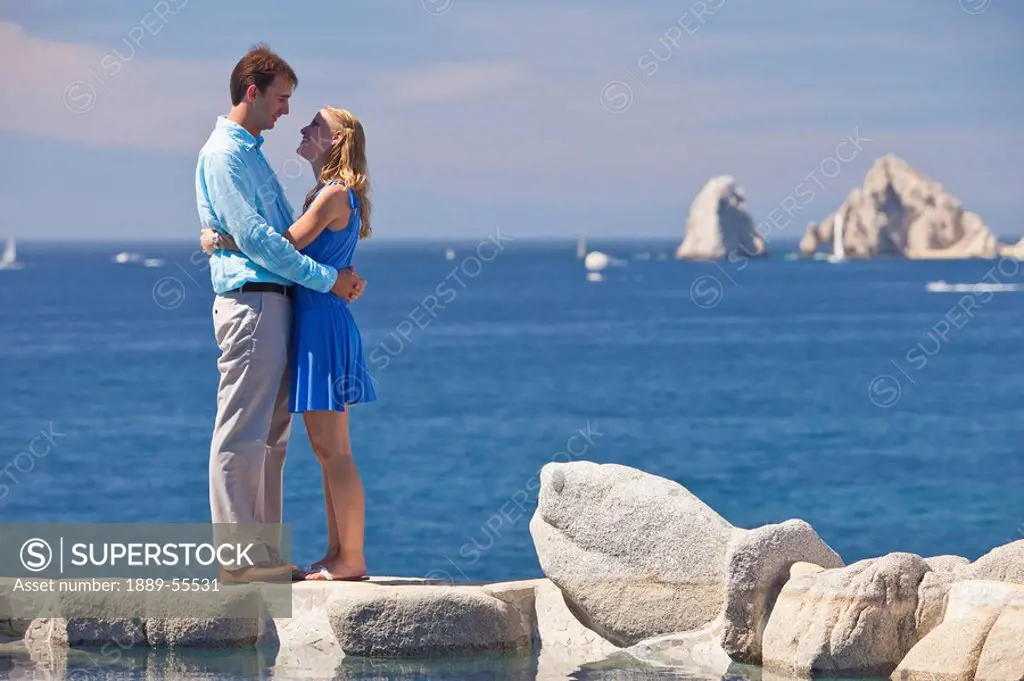 a couple in an embrace standing at the water´s edge, cabo san lucas, baja california, mexico