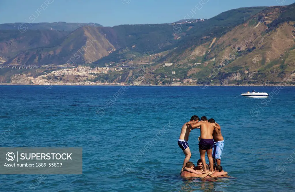 boys playing in the water, messina, sicily, italy