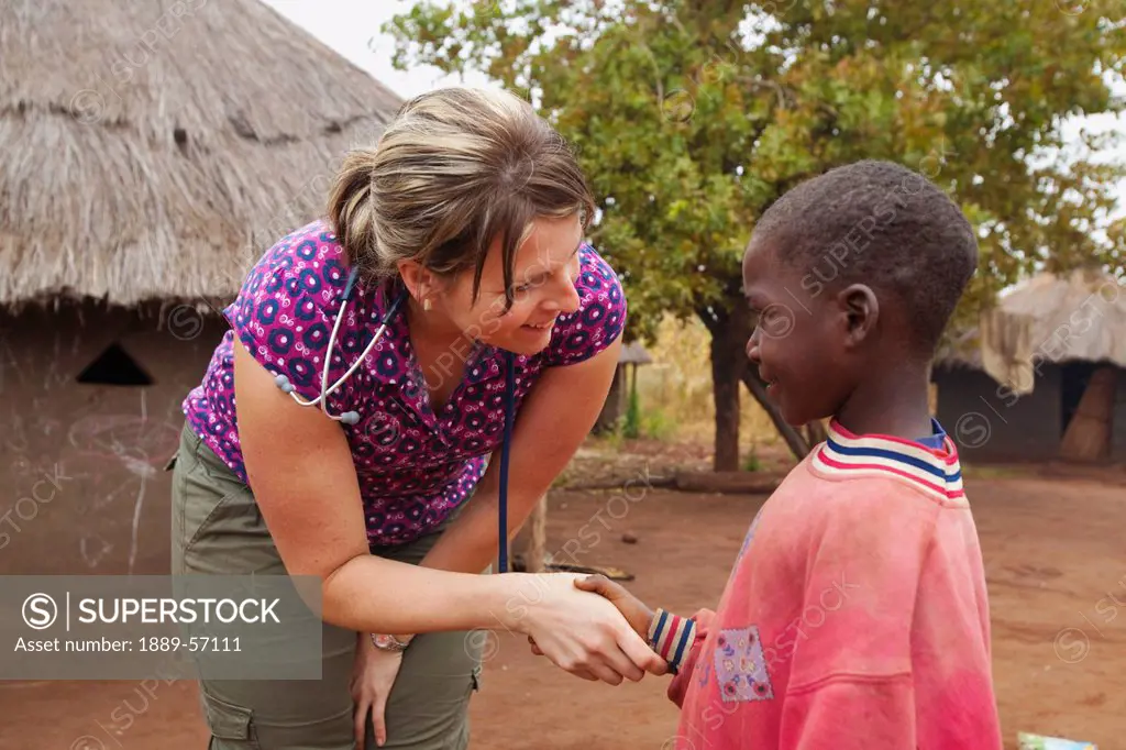 A Nurse Shakes The Hand Of A Boy, Manica, Mozambique, Africa