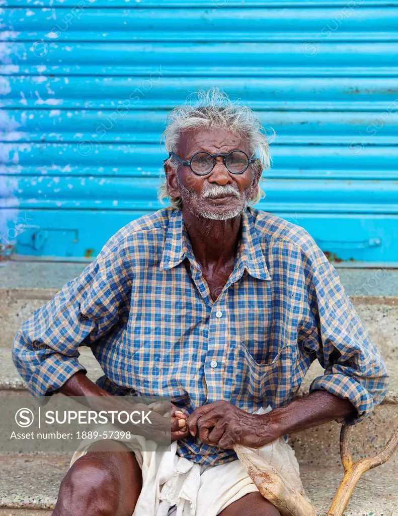 A Man Sitting On A Concrete Step And Working With His Hands, Sathyamangalam, Tamil Nadu, India