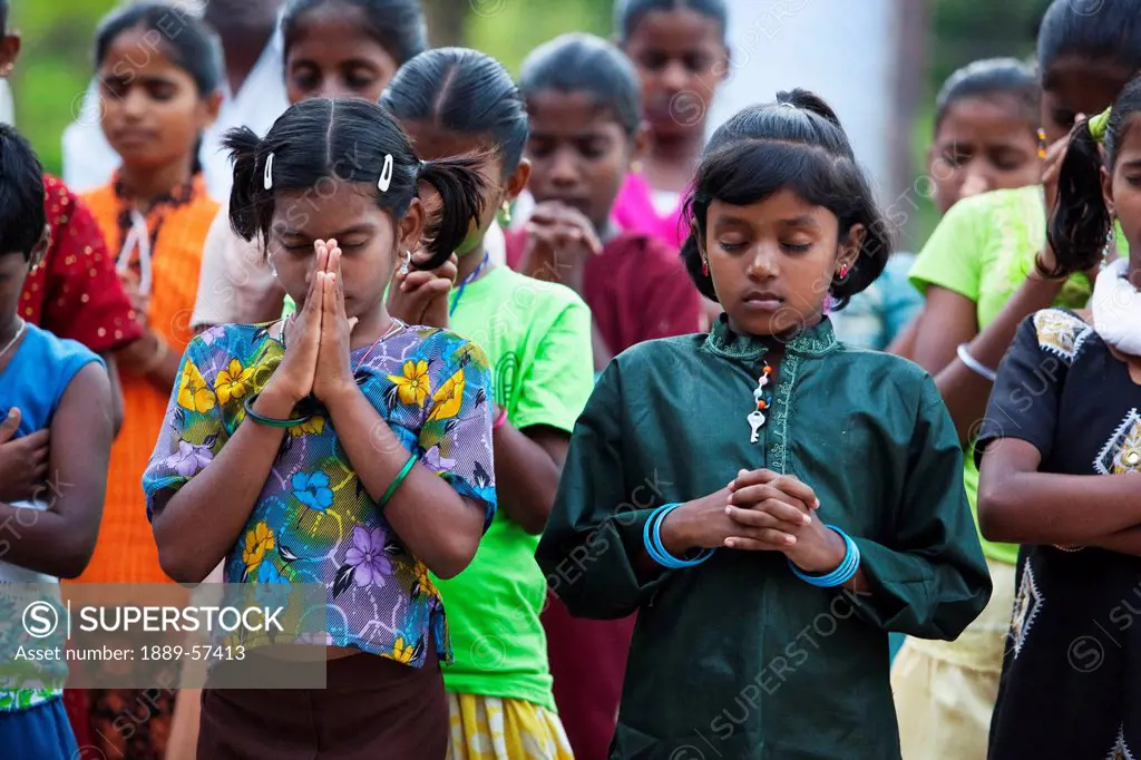 girls standing in rows with eyes closed in prayer, sathyamangalam, tamil nadu, india