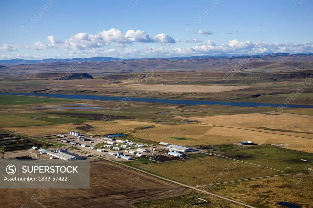 a farming colony in a river valley with foothills in the background, alberta, canada