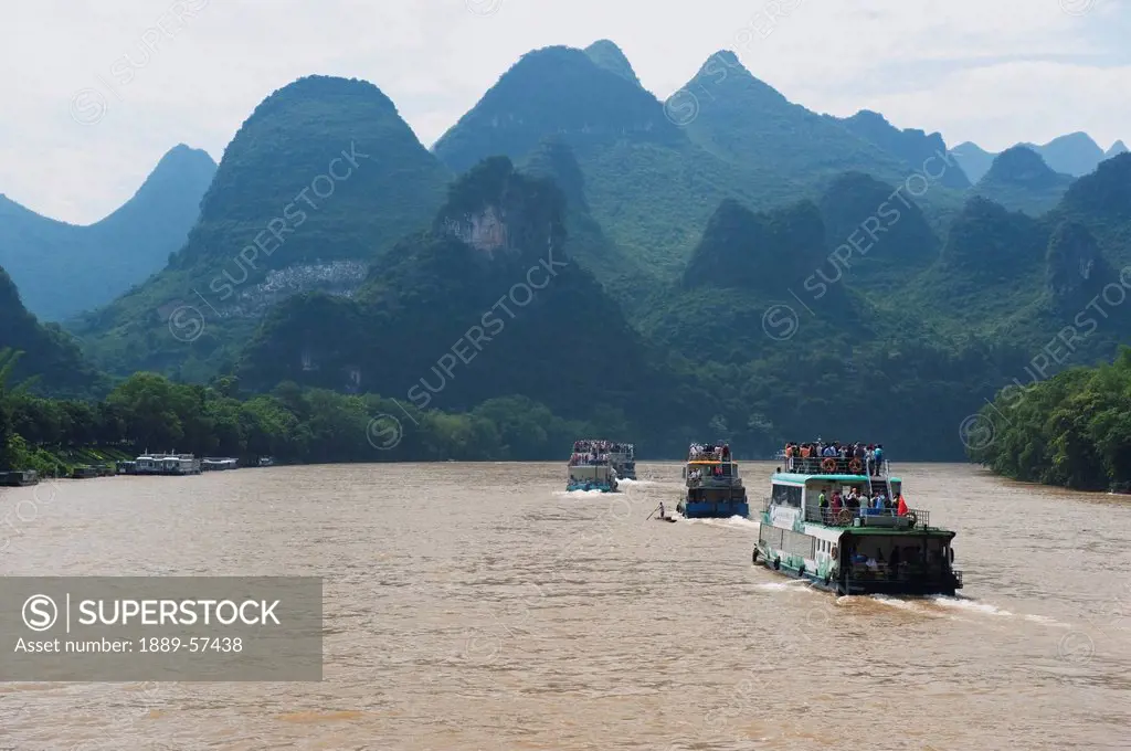 tour boats on river li near yangshuo, with karst formations in the background, guilin, guangxi, china