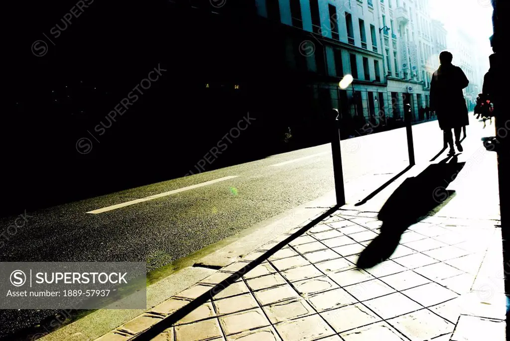 Silhouette and shadow of person walking on sidewalk, Paris, France