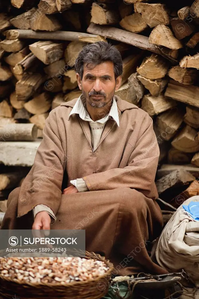 Merchant sitting in front of log pile