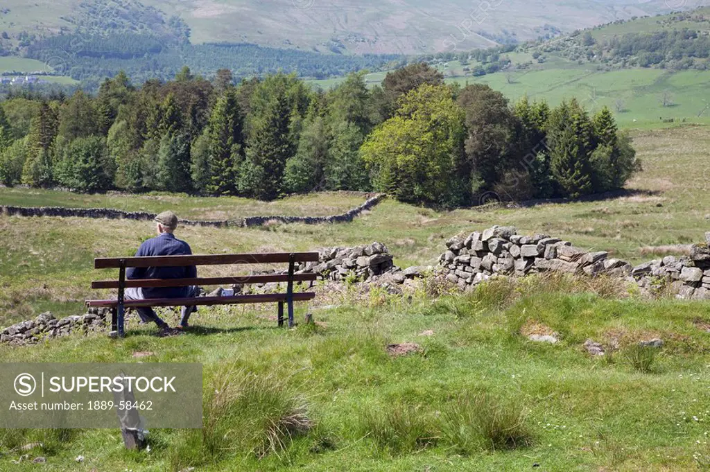 Man on bench in countryside, Dumfries and Galloway, Scotland