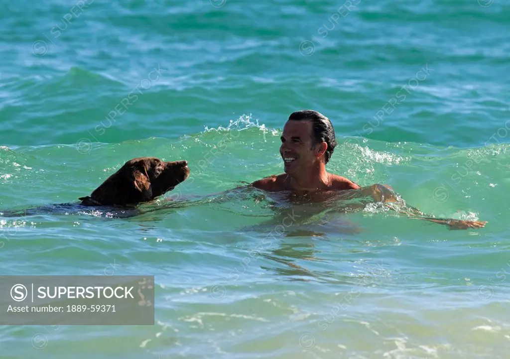 Man swimming with his dog in the ocean