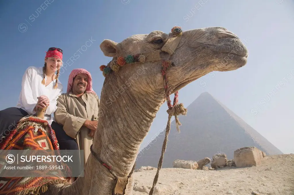 Young female tourist on a camel with a local guide at the Pyramids of Giza, Cairo, Egypt