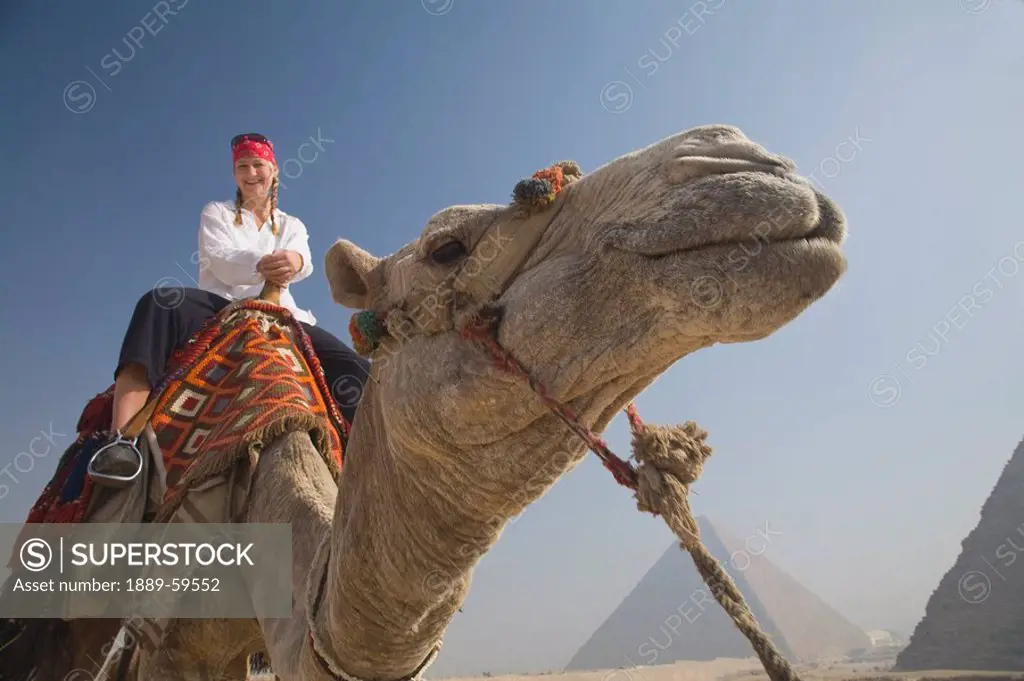 Young woman tourist on a camel at the Pyramids of Giza, Egypt