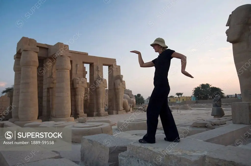 Woman tourist walks like an Egyptian at the Ramesseum, Luxor, Nile Valley, Egypt